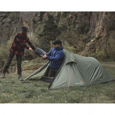 Reindal 2 tunneltält i naturmiljö, två personer bär in en sovsäck genom tältets öppna entré.