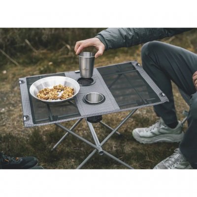 Litet och lågt bord med stålram och bordsskiva av polyester och mesh.